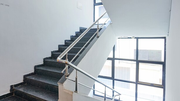 Eine Treppe mit Metallgeländer, das zu einer Zwischenebene führt.