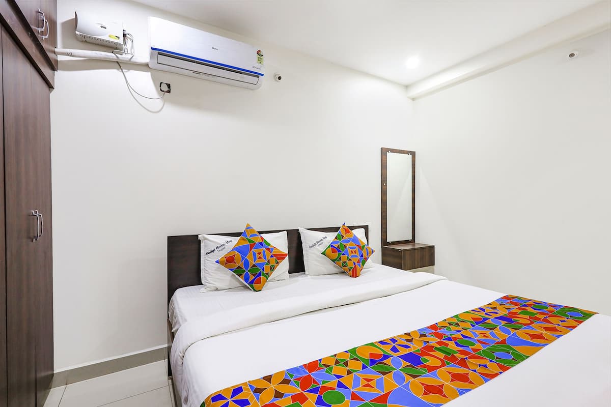 Quarto de hotel com uma cama, mesa de cabeceira, espelho, ar condicionado e guarda-roupa.