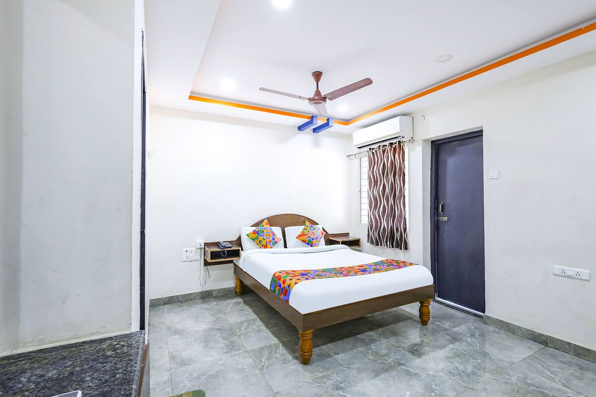 A bedroom with a bed, nightstands, a ceiling fan, and a door.