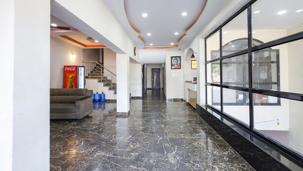 A modern lobby with a marble floor, a sofa, a Coca-Cola refrigerator, and a staircase. - FabExpress Sri Lakshmi Residency (Dehradun)