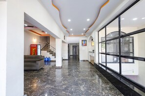 Un hall d’entrée moderne avec un sol en marbre, un canapé, un réfrigérateur rempli de Coca-Cola et un escalier.