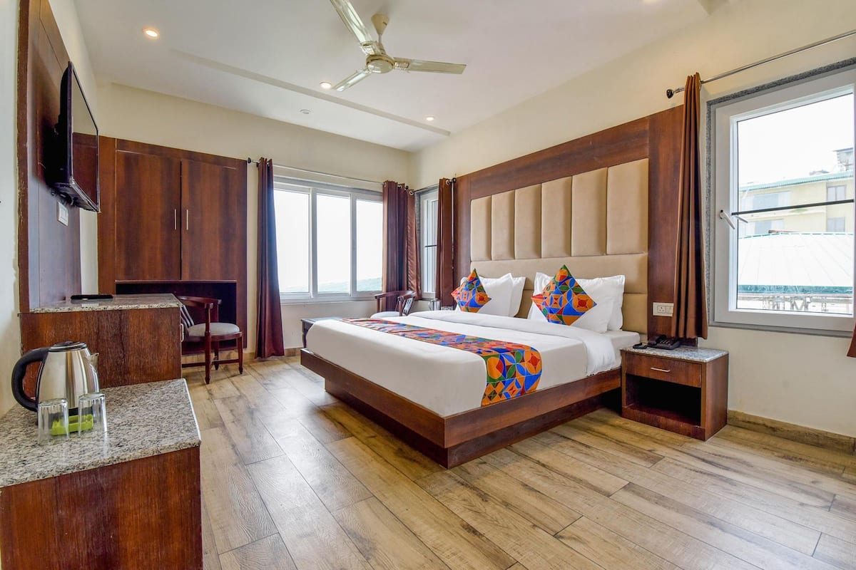 A modern hotel room with a large bed, a desk, and a TV.