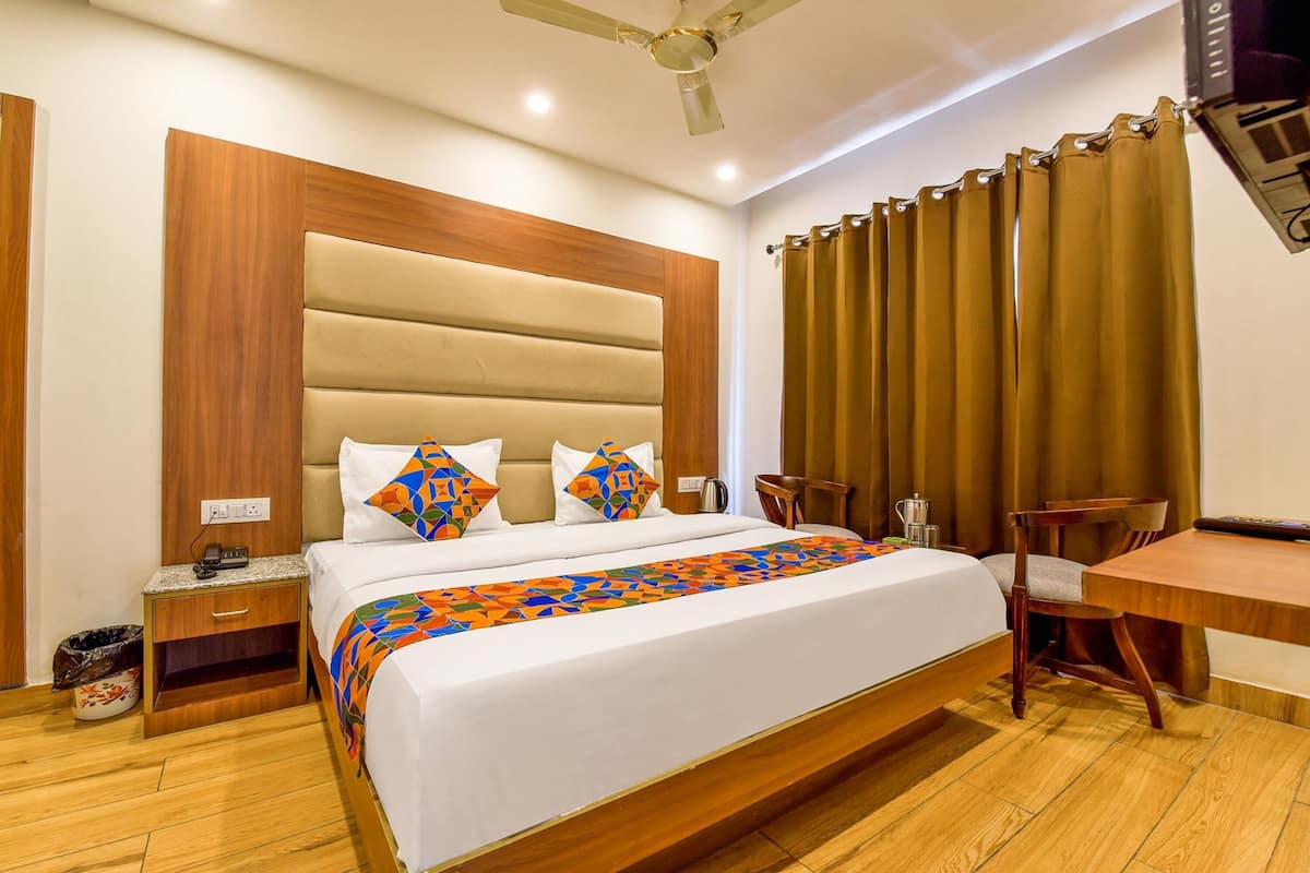 A hotel room with a large bed, wooden headboard, a desk, and a chair.