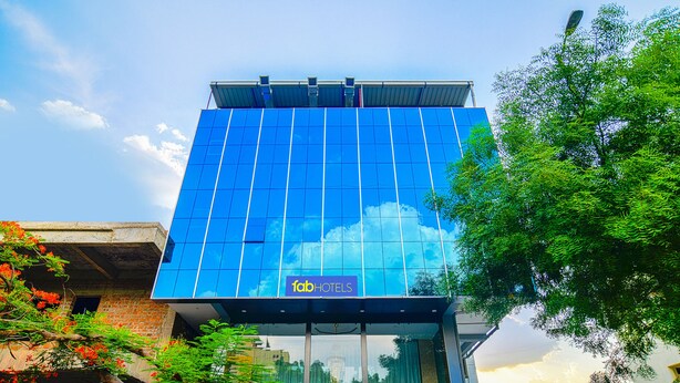 Un moderno edificio di hotel con area reception e facciata in vetro che riflette il cielo e le nuvole.