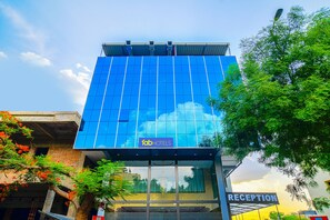 A modern hotel building with a reception area and a glass facade reflecting the sky and clouds. - FabHotel J Palace (Indore)
