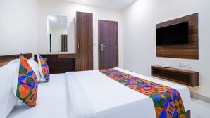 Una camera d'albergo con un letto, una TV a muro e uno specchio sopra il letto.
