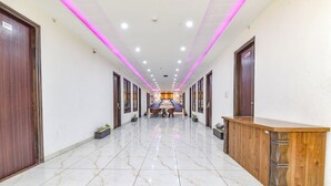 A hotel corridor with marble flooring, wooden reception desk, and doors on both sides. - FabHotel Jugnu (Kharar)