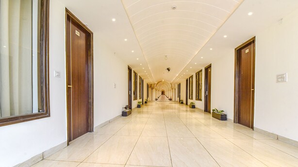 A long, well-lit hallway with multiple doors and potted plants. - FabHotel Jugnu (Kharar)