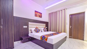 A modern bedroom with a large bed, a headboard, a nightstand, a wardrobe, and a painting on the wall. - FabHotel Jugnu (Kharar)
