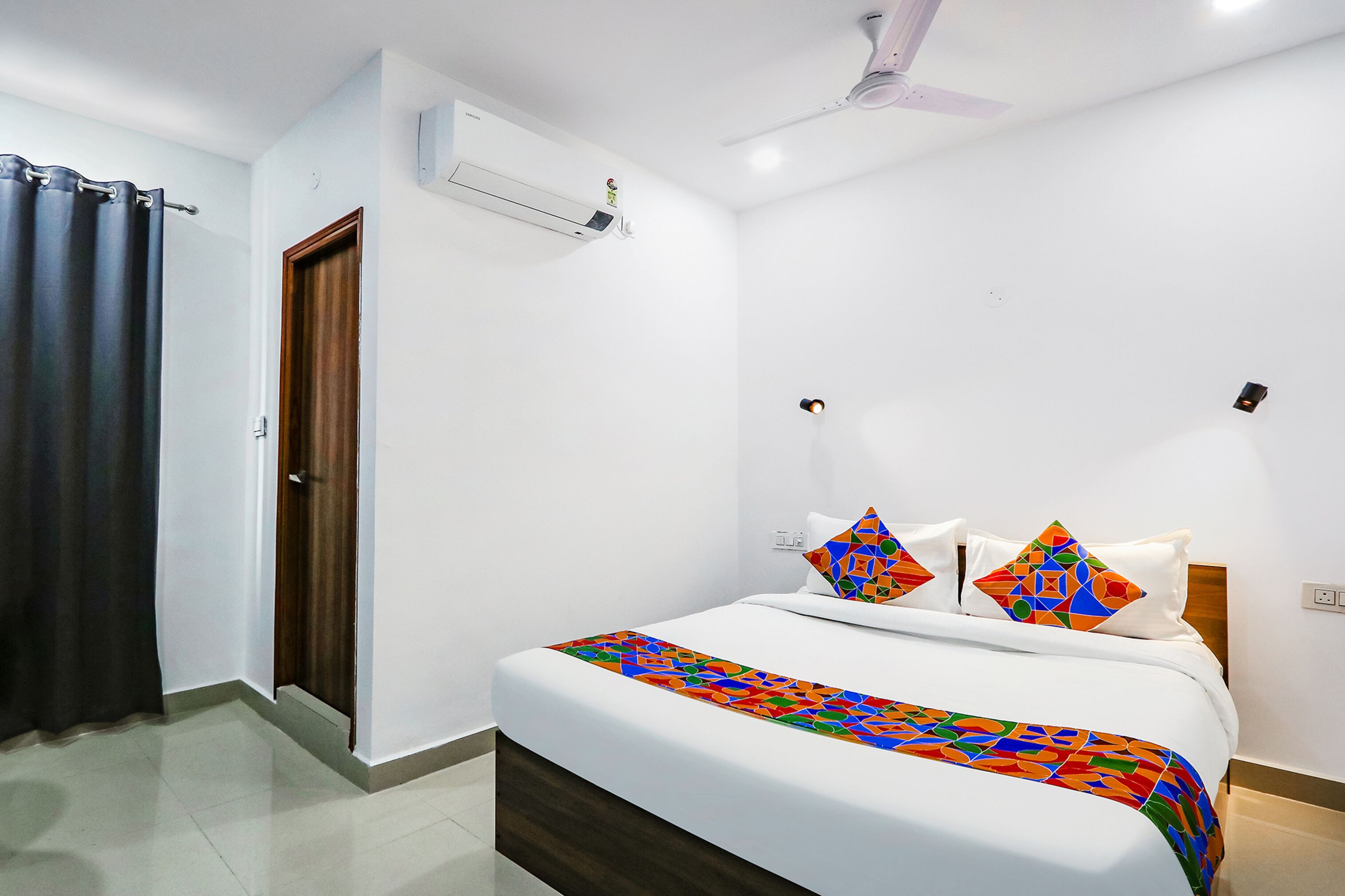 Een hotelkamer met een bed, een plafondventilator, een airconditioning en een deur.