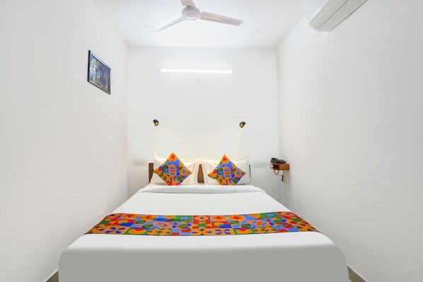 Une chambre à coucher avec un lit, un ventilateur de plafond, un climatiseur fixé au mur et un tableau encadré accroché au mur.