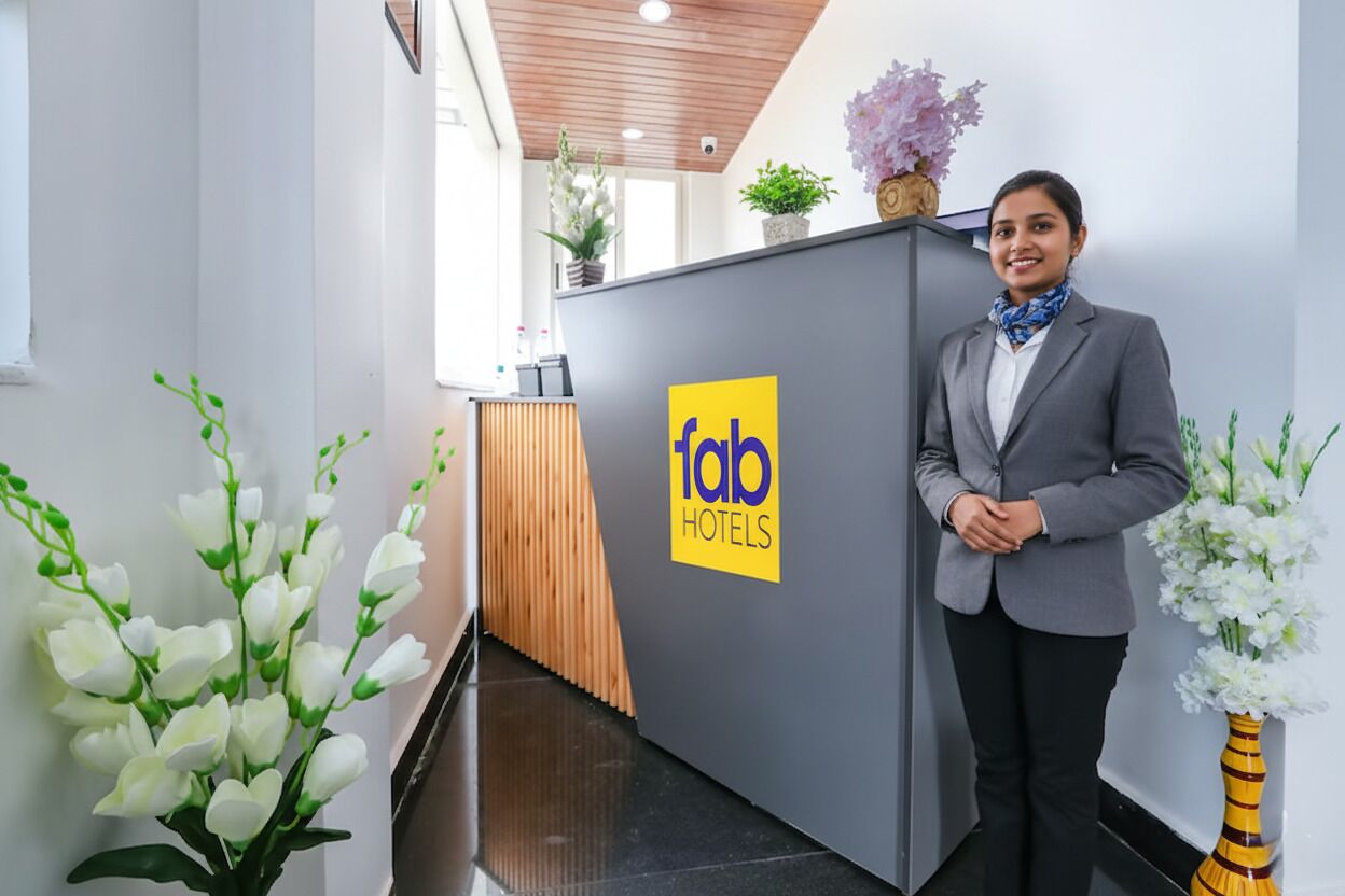 Un comptoir d’accueil orné du logo de « fab hotels », avec une personne debout à côté.