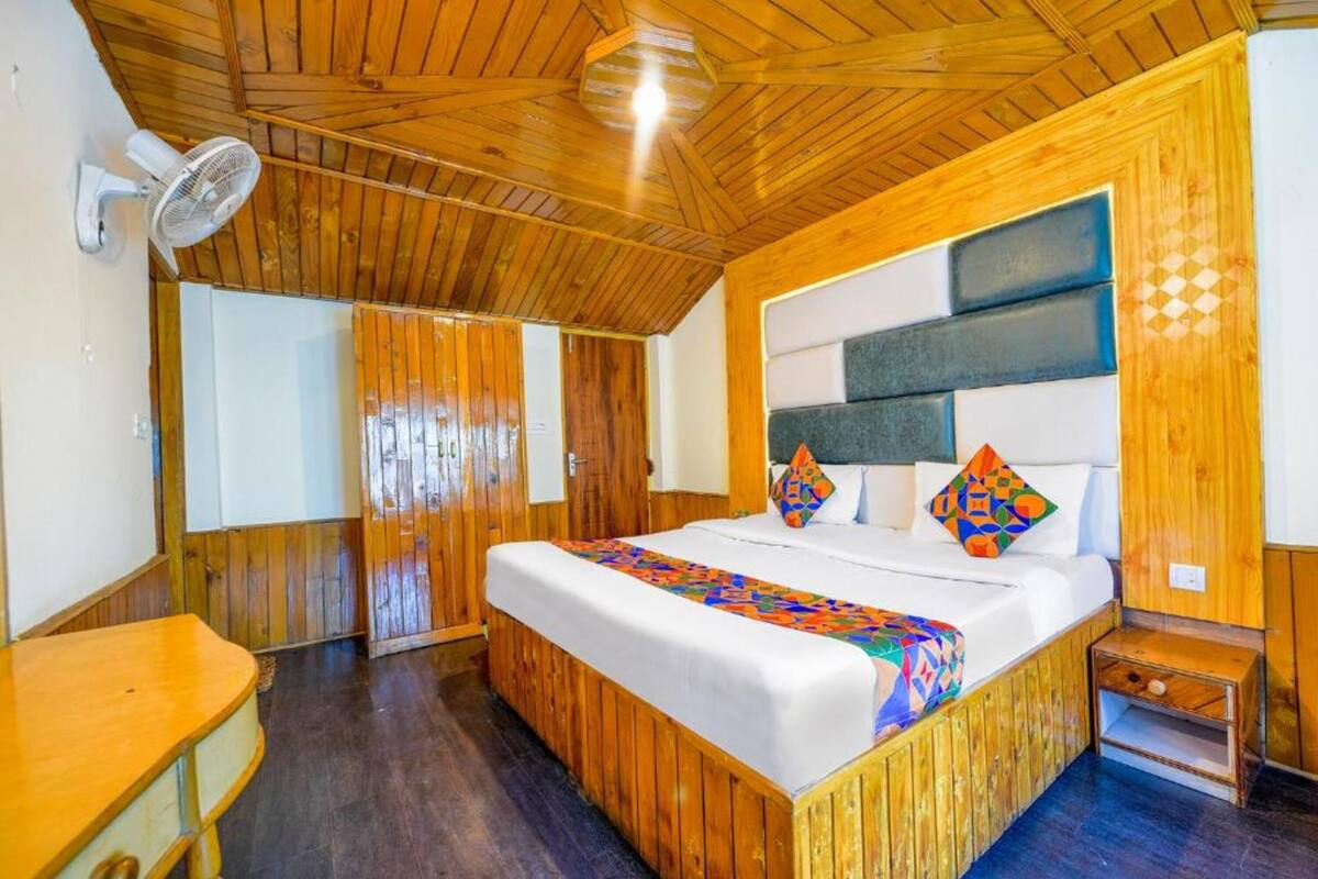 A wooden-paneled bedroom with a bed, a bedside table, and a wall-mounted fan.