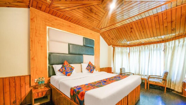 A wooden-paneled room with a bed, a nightstand, and a chair. - FabHotel Mountain View Cottage (Manali)