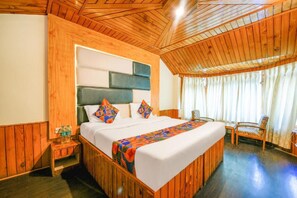 A wooden-paneled room with a bed, a nightstand, and a chair.