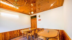 A dining area with wooden tables and chairs, a chandelier, and a wooden ceiling. - FabHotel Mountain View Cottage (Manali)