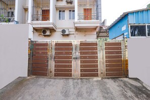 A gated entrance with a metal gate and a concrete pathway leading to a building with balconies and windows. - FabExpress Fen Breeze (Chennai)