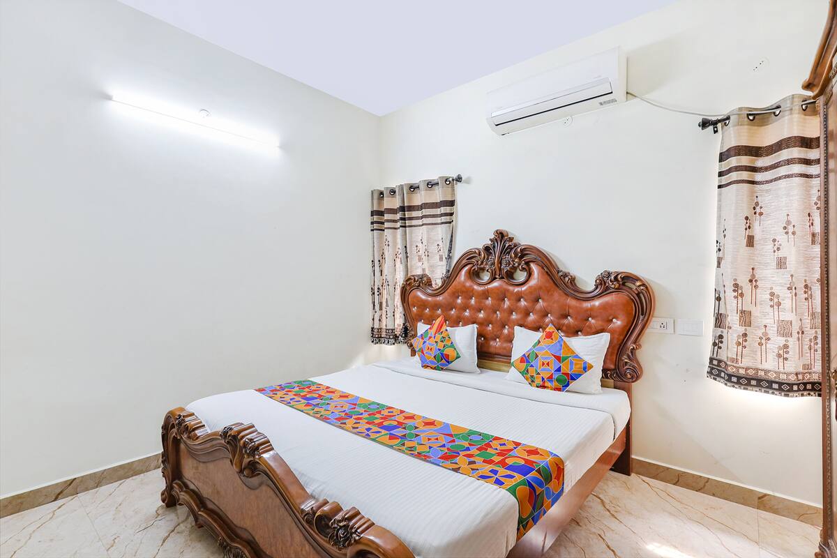 Uma cama bem arrumada com colcha estampada, cabeceira de madeira e dois travesseiros.