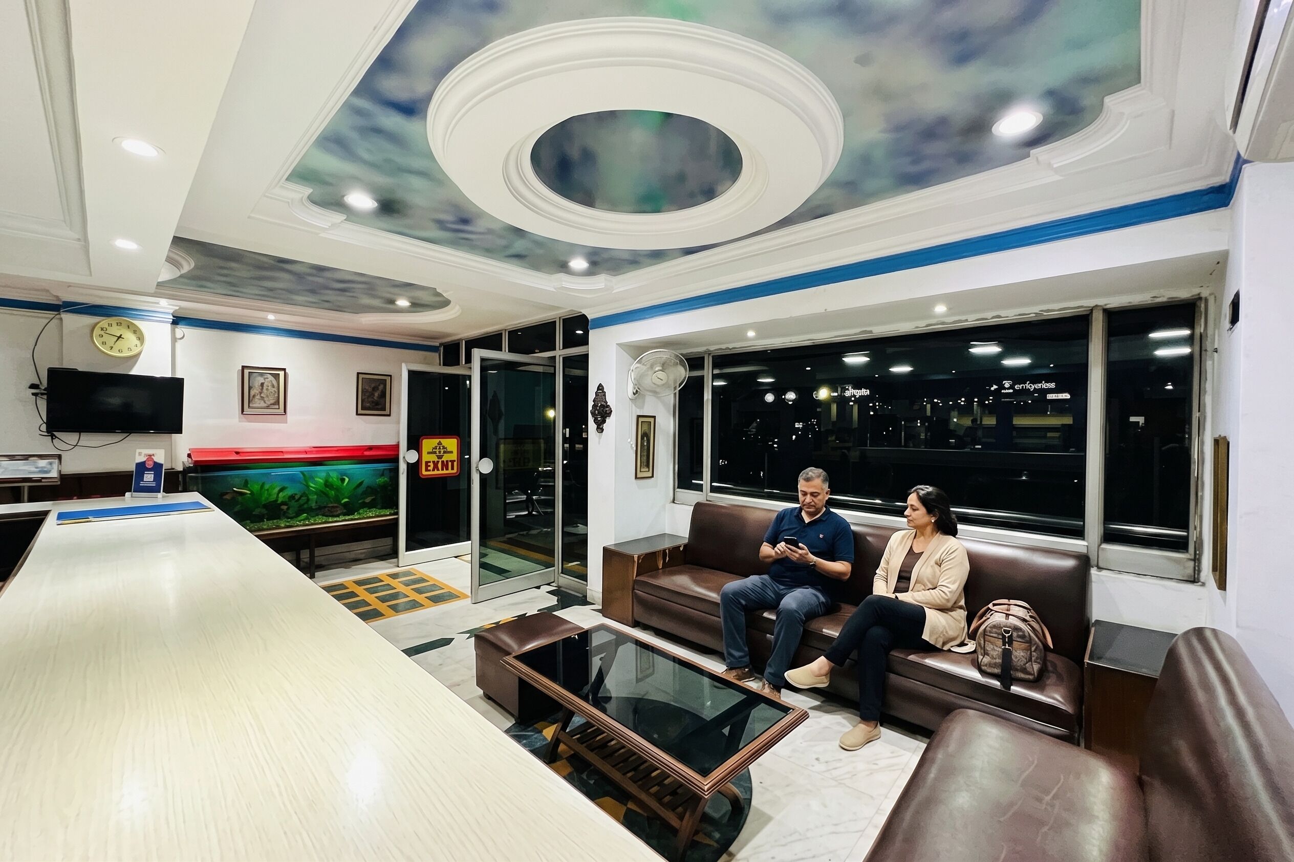 Un vestíbulo de hotel con una recepción, zona de estar y un gran acuario.