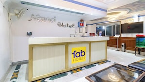 A hotel reception area with a counter, a clock, a television, and a decorative fish tank. - FabHotel Nand (Patna)