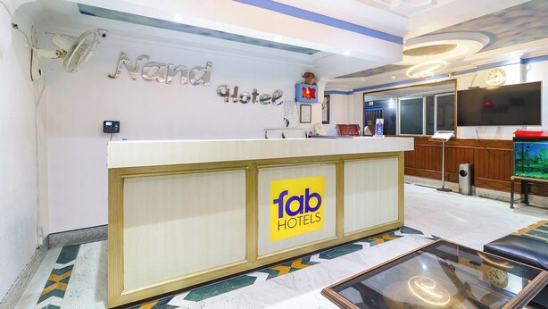 A hotel reception area with a counter, a clock, a television, and a decorative fish tank. - FabHotel Nand (Patna)