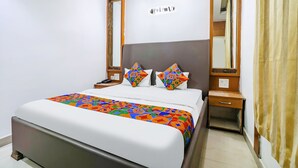 A neatly arranged hotel room with a large bed, two bedside tables, and two mirrors. - FabHotel Nand (Patna)