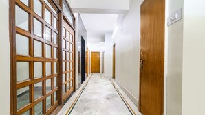 A hallway with a marble floor, wooden doors, and a view into adjacent rooms. - FabHotel Nand (Patna)