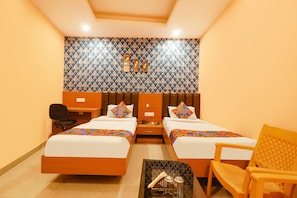 A hotel room with two beds, a desk, a chair, and a small table.