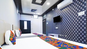 Une chambre d’hôtel avec un grand lit, un téléviseur fixé au mur et un papier peint à motifs.