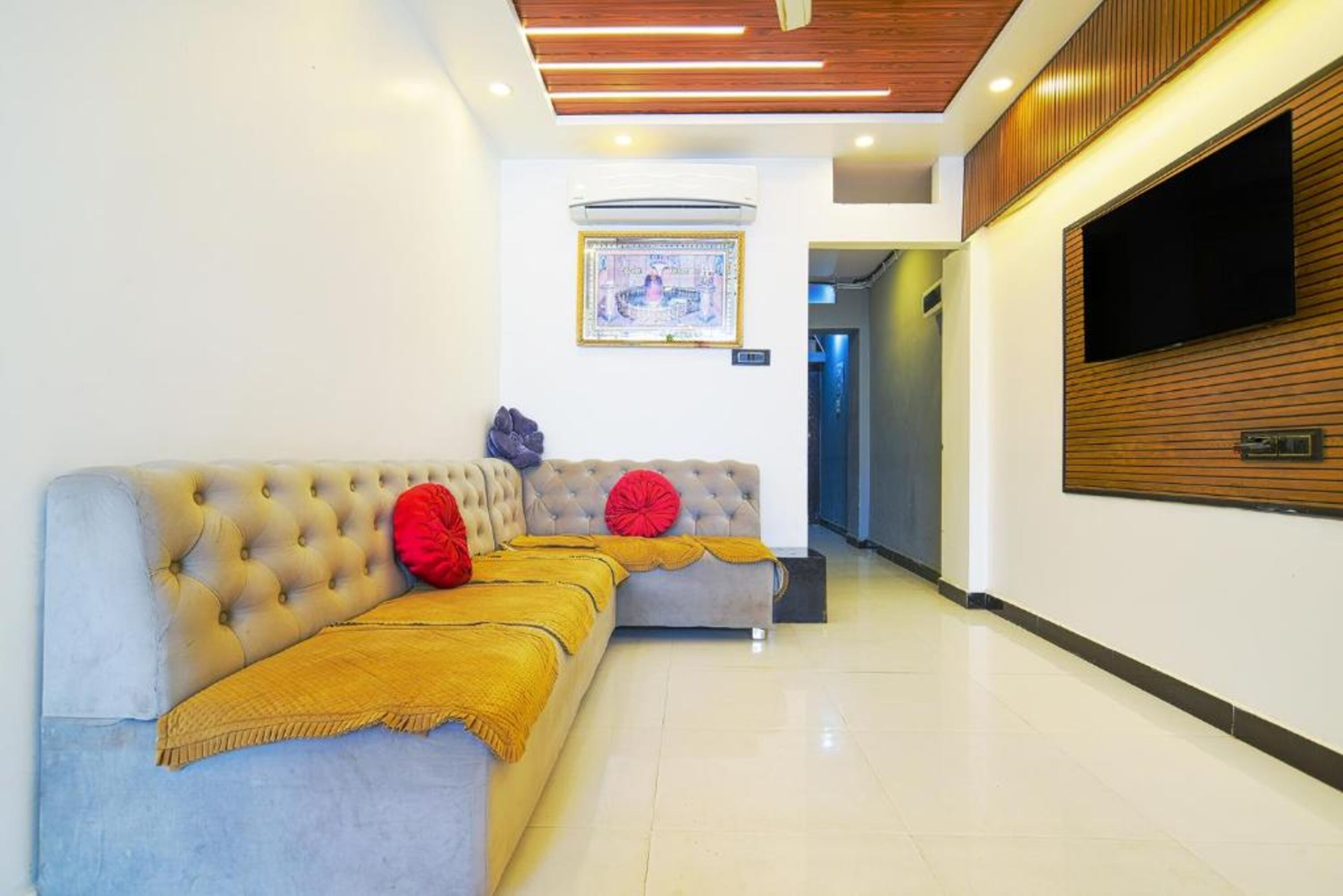 A modern lobby with a sofa, a television, and an air conditioning unit.