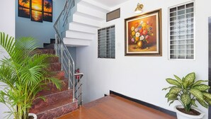 Un escalier avec une rampe en métal, une plante en pot et un tableau accroché au mur.