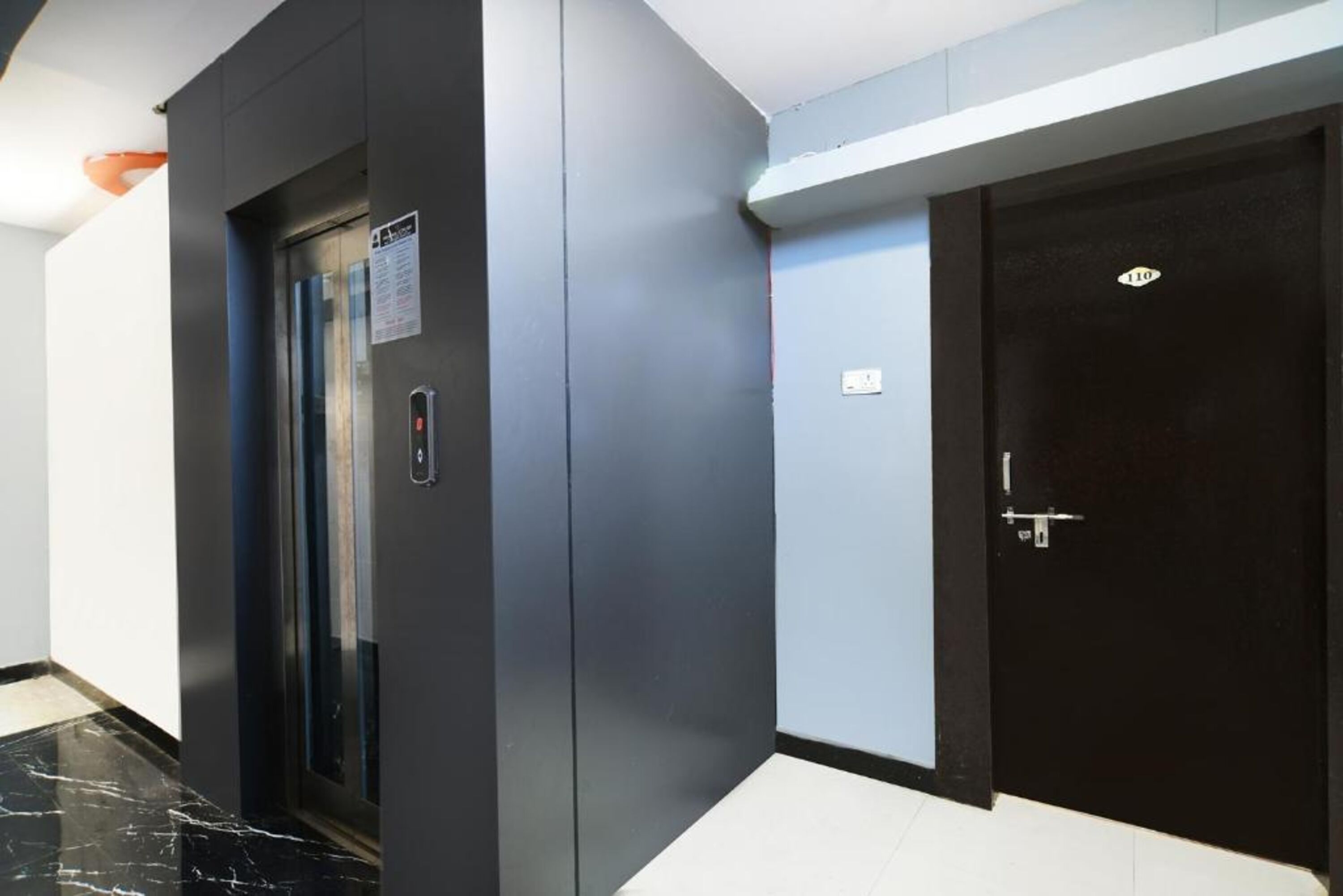 Un ascenseur moderne et une porte avec une plaque indiquant le numéro.
