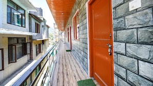 A corridor with stone walls and wooden ceiling, leading to an orange door. - FabHotel Chand Palace (Manali)