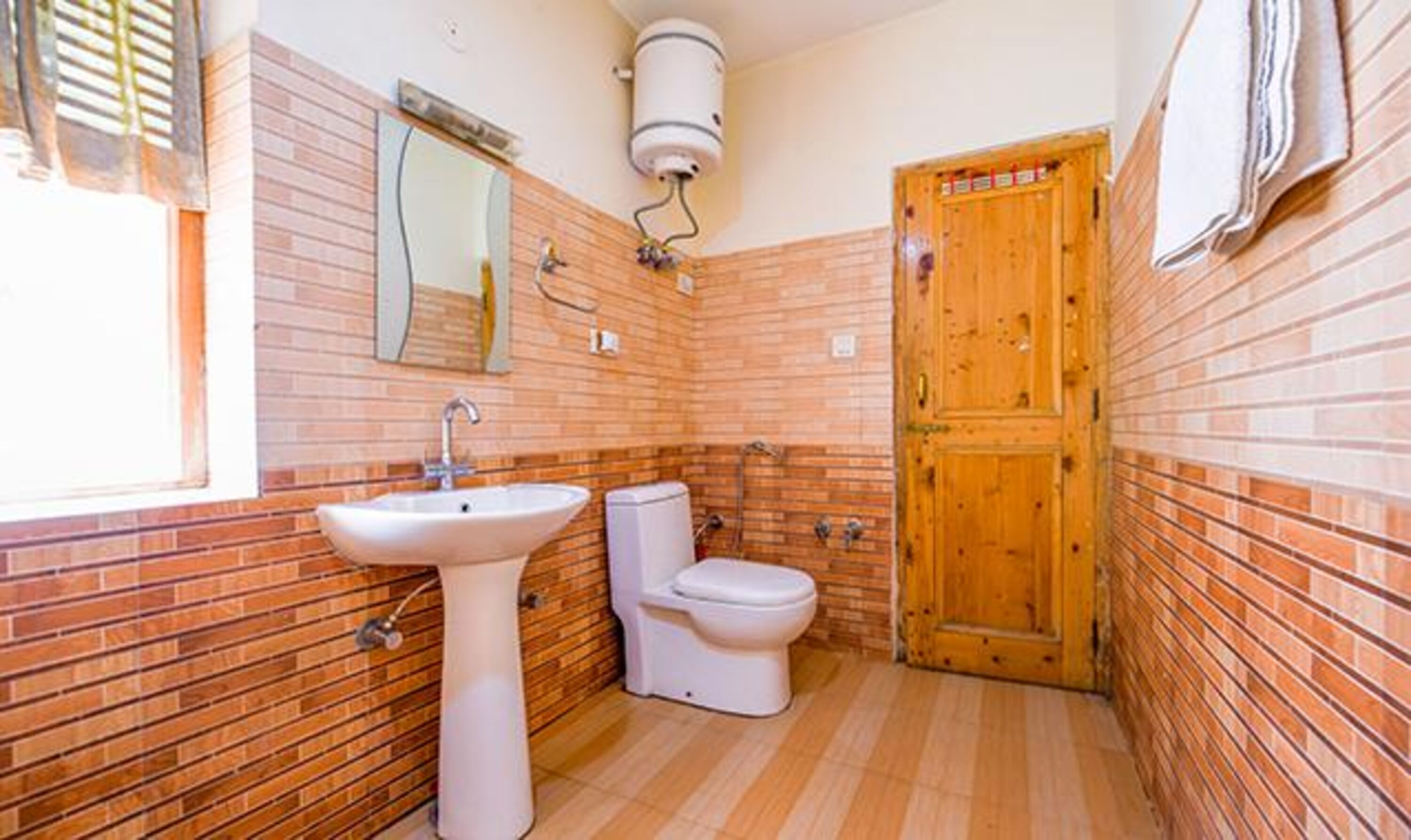 A bathroom with a sink, toilet, and wooden door.