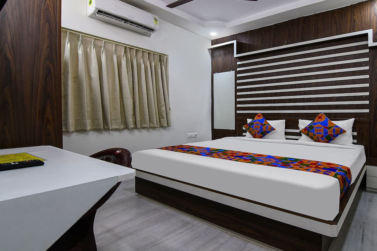A modern hotel room with a large bed, a desk, and a wardrobe.