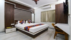 A bedroom with a bed, bedside table, chair, and a desk. - FabHotel Majestic Suite (Barasat)