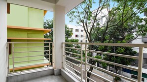 A balcony with a view of a tree-lined street and buildings. - FabHotel Majestic Suite (Barasat)