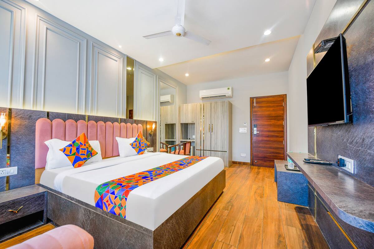 A modern hotel room with a large bed, a desk, a flat-screen TV, and a ceiling fan.