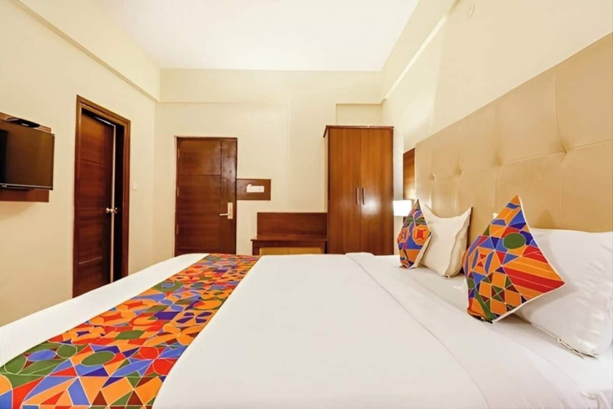 A hotel room with a bed, a television, a wardrobe, and a door.
