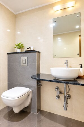 A modern bathroom with a toilet, sink, and mirror. - Hotel Magaji Comfort Inn (Bengaluru)