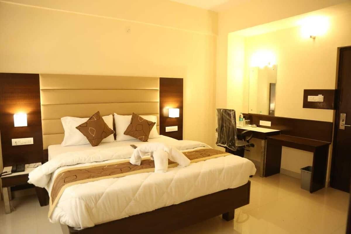 A hotel room with a large bed, a desk, a mirror, and a nightstand.