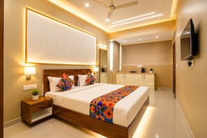 A modern hotel room with a bed, bedside table, and a large mirror. - Hotel Magaji Comfort Inn (Bengaluru)