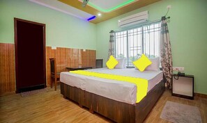 A bedroom with a wooden bed, a window with curtains, and an air conditioning unit. - FabHotel Utsho (Jalpaiguri)