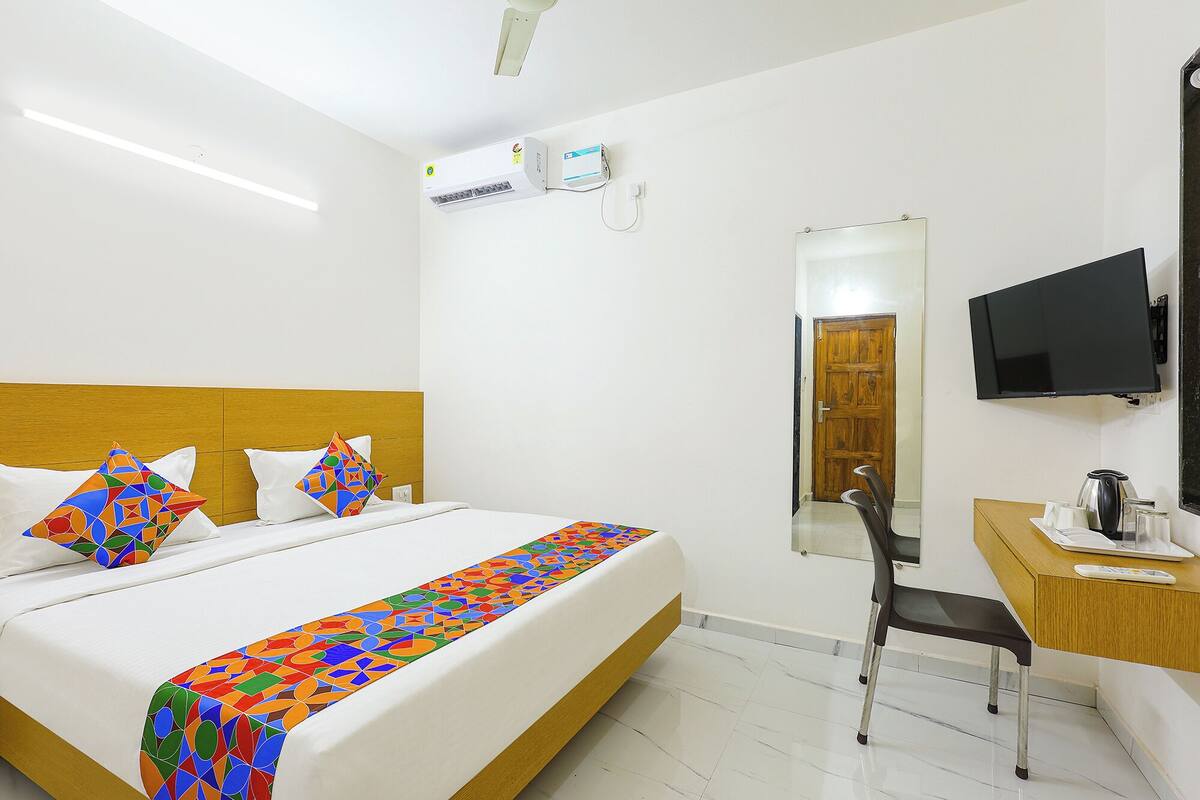 Une chambre d’hôtel équipée d’un lit, d’un bureau, d’une chaise, d’une télévision et d’un appareil de climatisation.