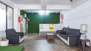 A reception area with a green wall, two sofas, a small table, a water dispenser, and a fire extinguisher. - FabHotel Atithi Regency (Pune)