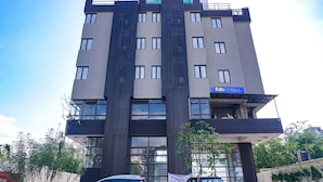 A multi-story hotel with a modern design, featuring a prominent vertical strip of dark material on the facade, large windows, and a sign indicating it is a hotel. - FabHotel Atithi Regency (Pune)