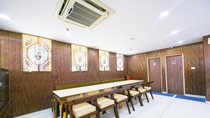 Een vergaderruimte met een lange tafel en stoelen, houten paneelwanden en een airconditioning.