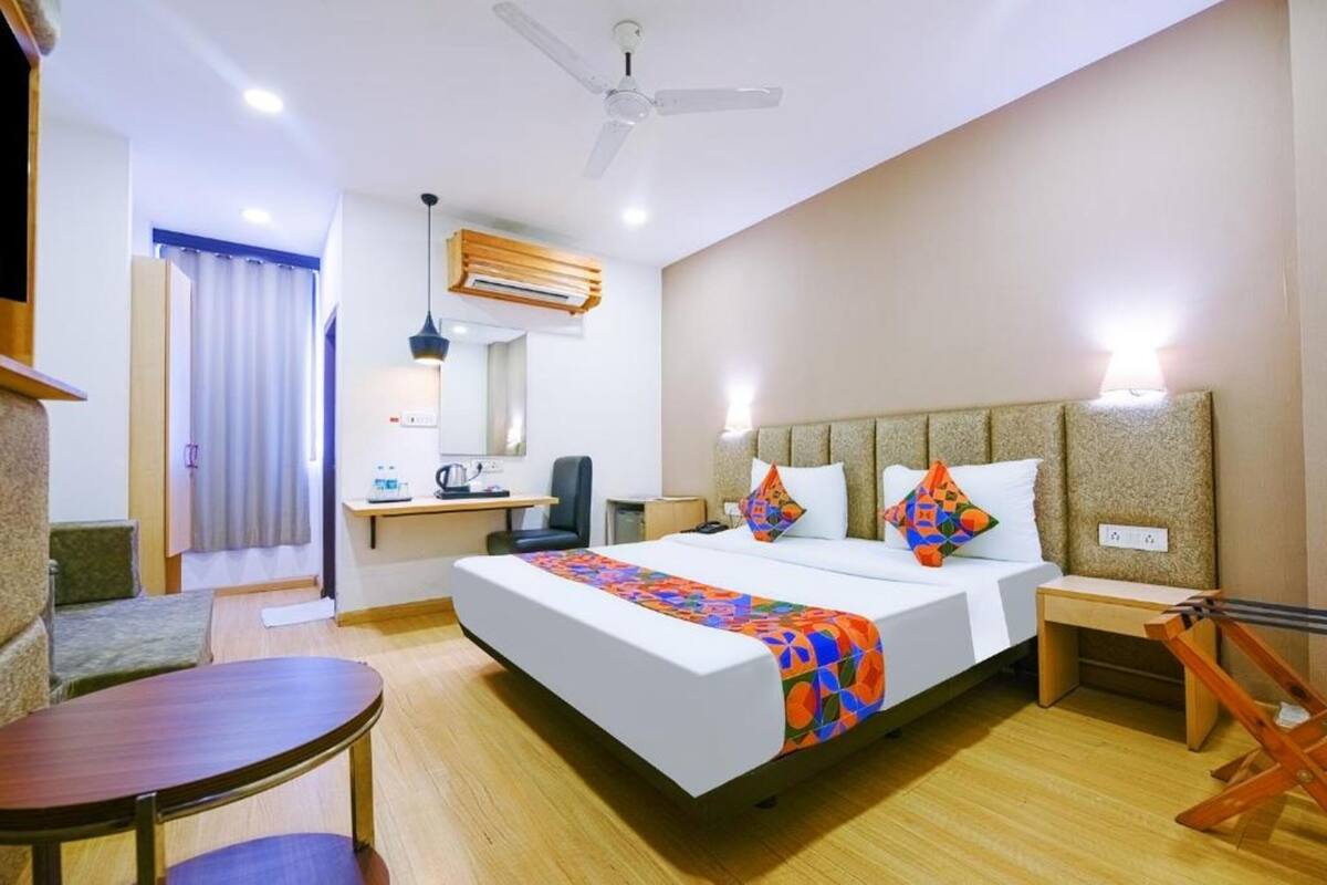 Ein Hotelzimmer mit einem Bett, einem Schreibtisch, einem Sessel, einem kleinen Tisch, einem Deckenventilator und einer Klimaanlage.