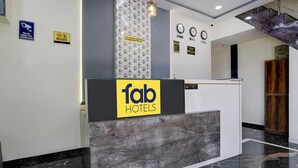A reception desk with a 'fab hotels' sign, a CCTV surveillance sign, a 'no alcohol' sign, and a clock on the wall. - FabExpress Golden Sands inn (Mumbai)