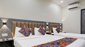 A hotel room with a large bed, two bedside tables, and a headboard with geometric patterns. - FabExpress Golden Sands inn (Mumbai)
